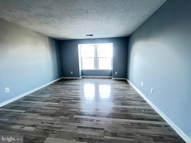 empty room featuring a textured ceiling and dark hardwood / wood-style floors