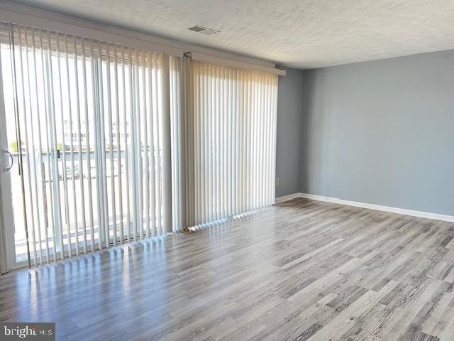 spare room featuring wood-type flooring and a textured ceiling