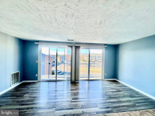 unfurnished room with a textured ceiling and dark hardwood / wood-style flooring