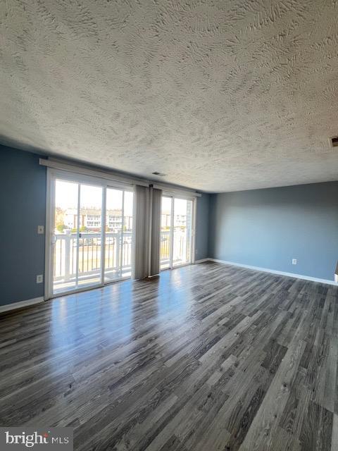 spare room with a textured ceiling and dark hardwood / wood-style floors