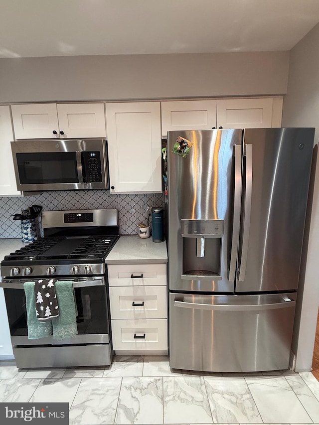 kitchen with decorative backsplash, white cabinets, and appliances with stainless steel finishes