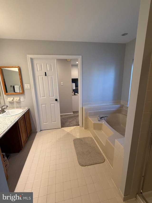 bathroom with a tub to relax in, tile patterned flooring, and vanity