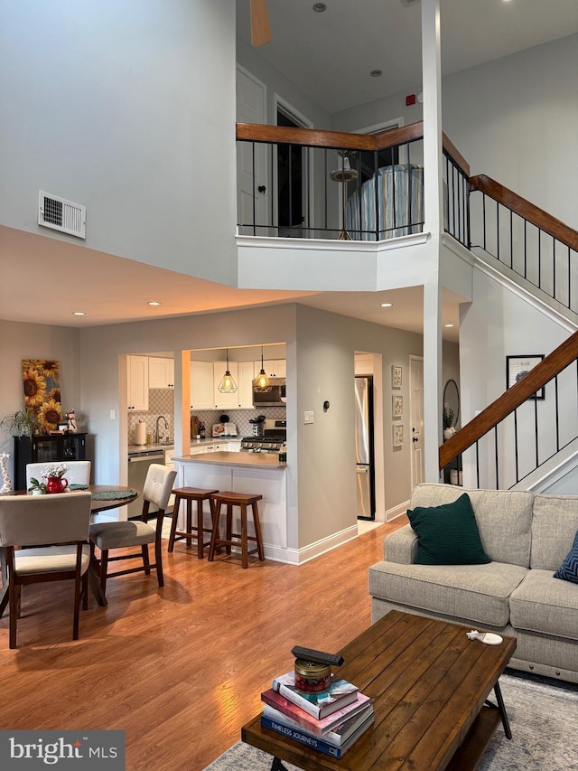 living room featuring light hardwood / wood-style flooring, a high ceiling, and sink