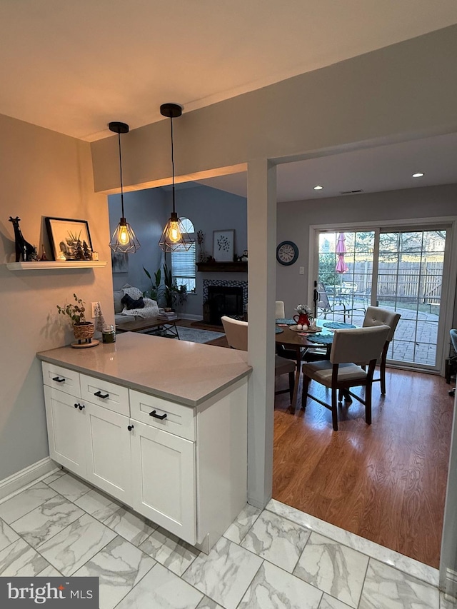 kitchen featuring pendant lighting, white cabinetry, and a tile fireplace