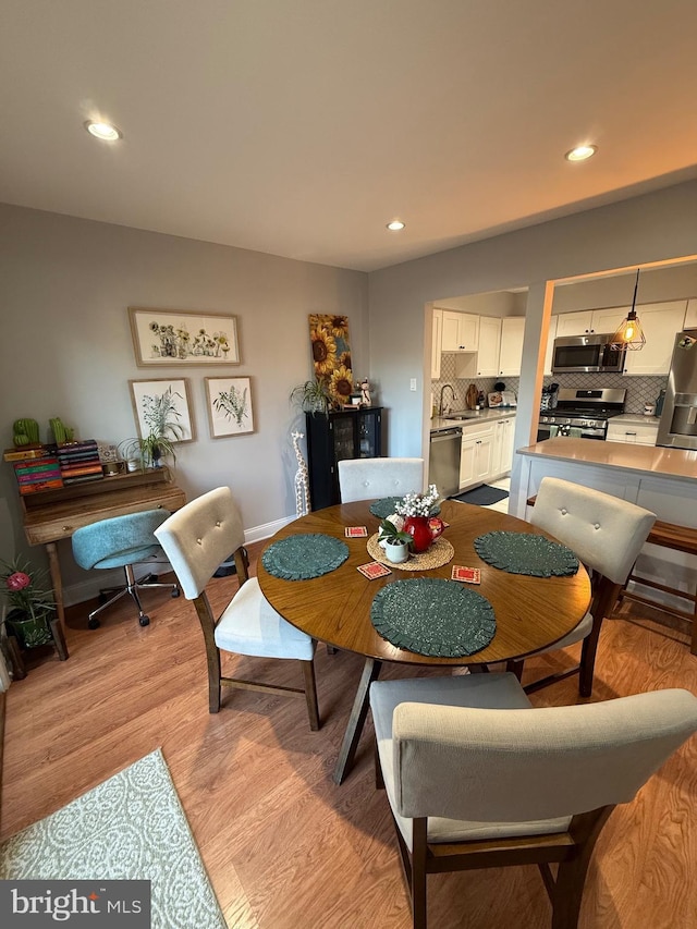 dining space with light hardwood / wood-style flooring and sink