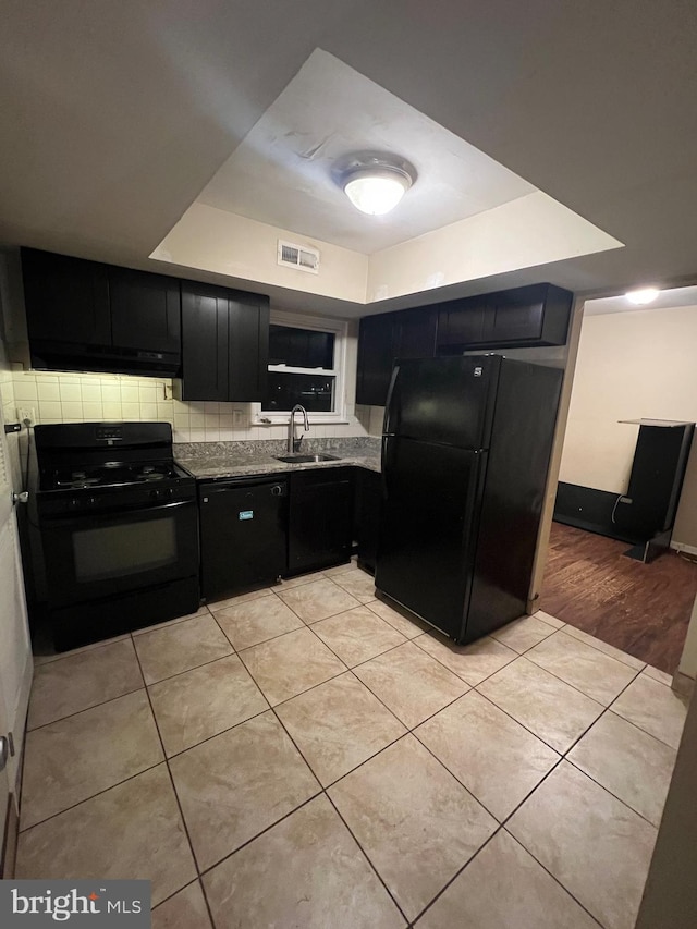 kitchen featuring black appliances, sink, light stone countertops, a tray ceiling, and light tile patterned flooring