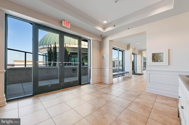 interior space featuring ornamental molding, a raised ceiling, and light tile patterned flooring