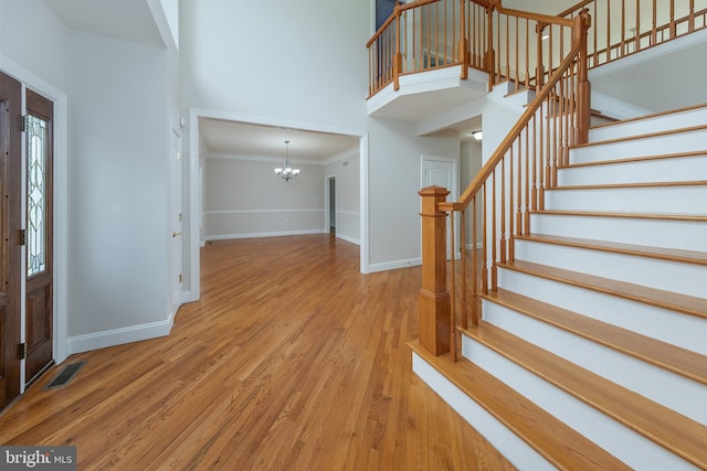 foyer featuring light wood-type flooring, crown molding, and a notable chandelier