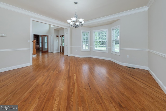 empty room with crown molding, a chandelier, and wood-type flooring