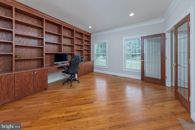 unfurnished office with light hardwood / wood-style flooring, built in desk, ornamental molding, and french doors