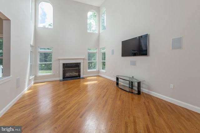 unfurnished living room featuring a high end fireplace, a high ceiling, and plenty of natural light