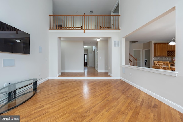 unfurnished living room featuring a high ceiling and light hardwood / wood-style flooring