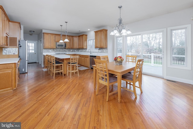 dining space featuring a notable chandelier, light hardwood / wood-style floors, and sink