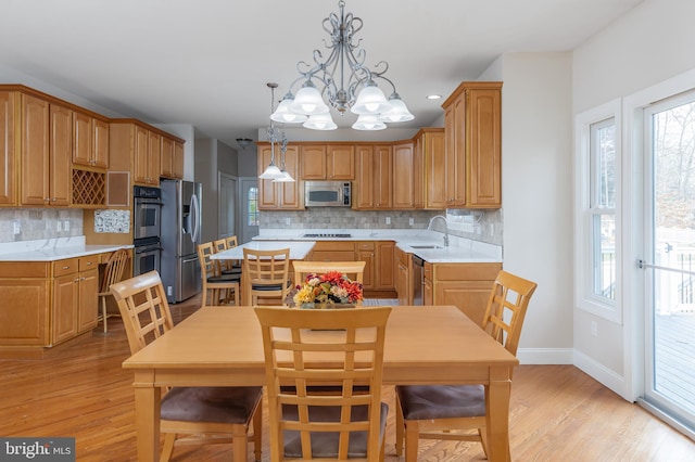 kitchen featuring backsplash, stainless steel appliances, sink, pendant lighting, and an inviting chandelier