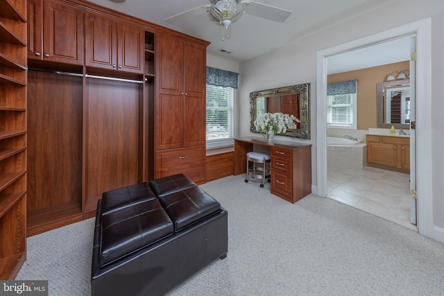 office space with ceiling fan, sink, built in desk, and light carpet