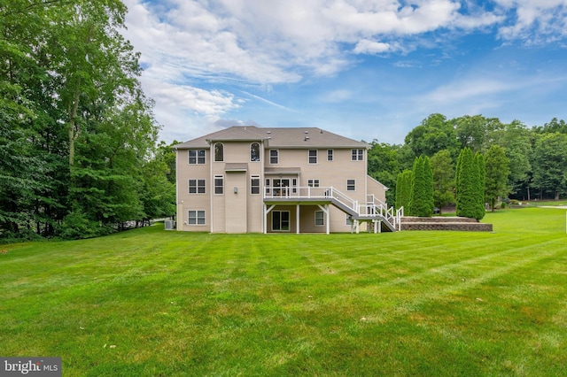 rear view of house with a wooden deck and a yard