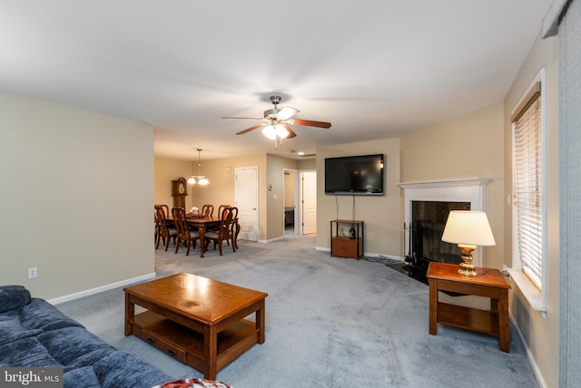 living room featuring a high end fireplace, ceiling fan with notable chandelier, and carpet floors