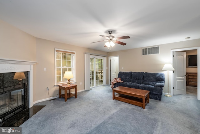 carpeted living room featuring a premium fireplace and ceiling fan