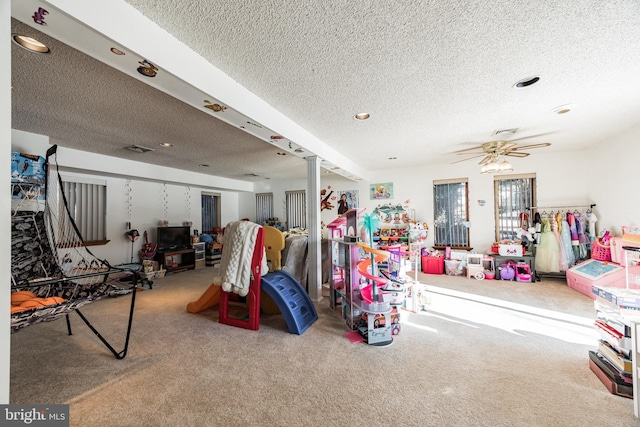 rec room with carpet, a textured ceiling, and ceiling fan