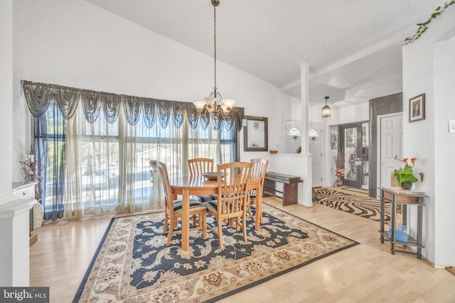 dining room featuring hardwood / wood-style floors, lofted ceiling, and a notable chandelier