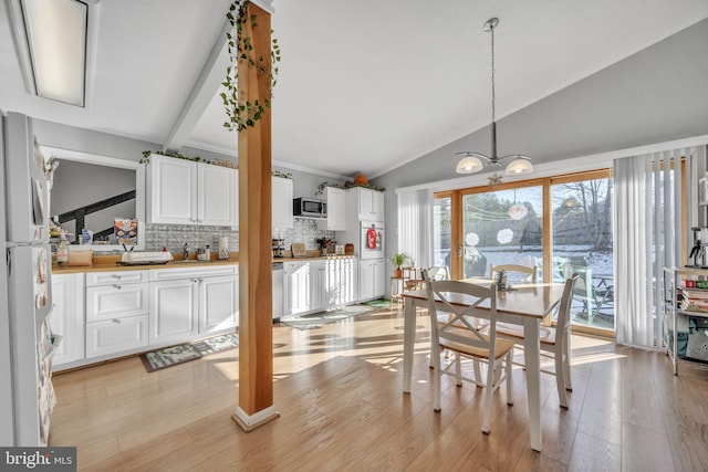 dining area featuring vaulted ceiling with beams, light hardwood / wood-style flooring, and an inviting chandelier