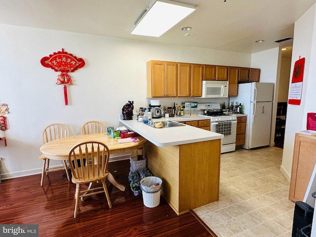 kitchen with kitchen peninsula, sink, and white appliances