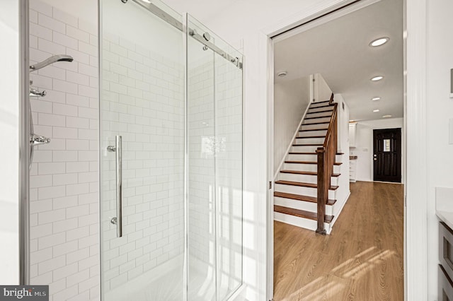 bathroom with a shower with door and hardwood / wood-style floors