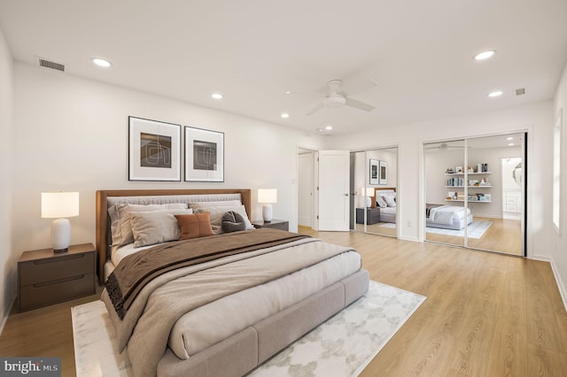 bedroom featuring light wood-type flooring, two closets, and ceiling fan