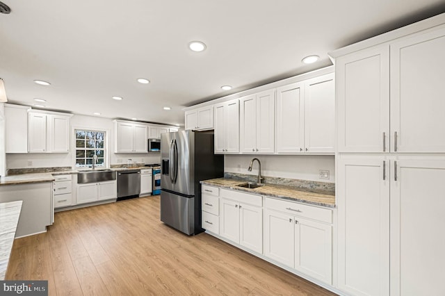 kitchen featuring appliances with stainless steel finishes, light hardwood / wood-style floors, sink, and white cabinets