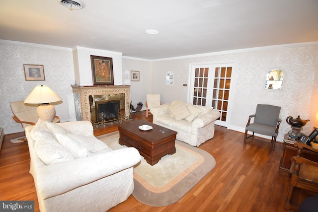 living room with dark wood-type flooring, a premium fireplace, crown molding, and french doors