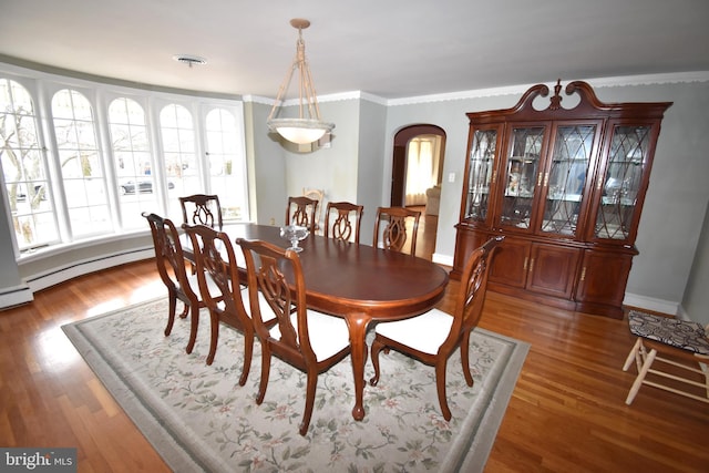 dining space with wood-type flooring, ornamental molding, and a baseboard radiator