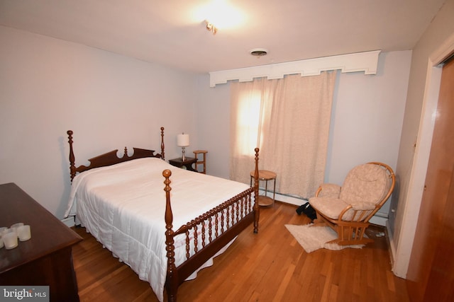 bedroom with hardwood / wood-style flooring and baseboard heating