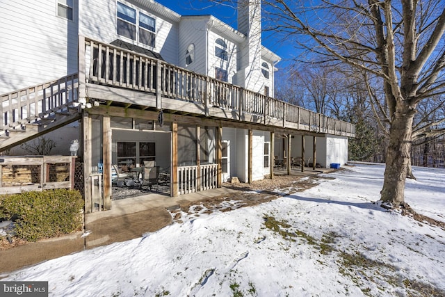 snow covered back of property with a patio area