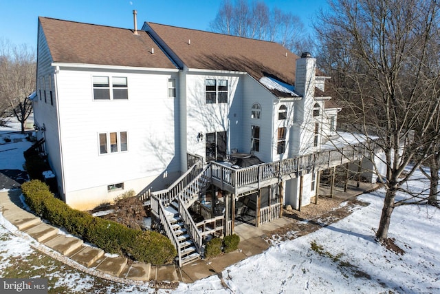 snow covered back of property with a wooden deck