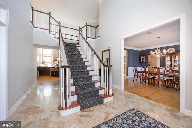 stairway featuring hardwood / wood-style floors, ornamental molding, and an inviting chandelier