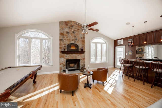 living room with a stone fireplace, lofted ceiling, billiards, and light hardwood / wood-style flooring