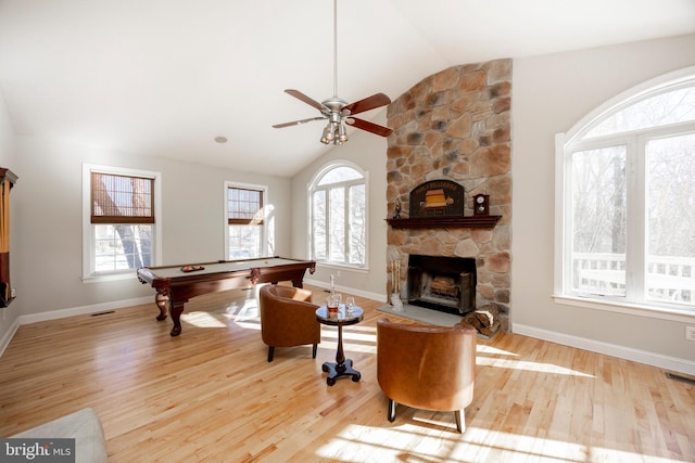 game room featuring vaulted ceiling, a stone fireplace, a healthy amount of sunlight, and billiards