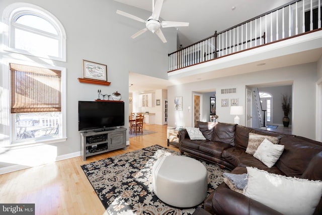 living room featuring plenty of natural light, ceiling fan, and a towering ceiling