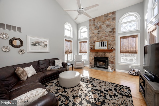 living room featuring a fireplace, light hardwood / wood-style floors, high vaulted ceiling, and ceiling fan