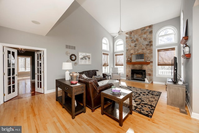 living room with a fireplace, ceiling fan with notable chandelier, hardwood / wood-style flooring, and high vaulted ceiling