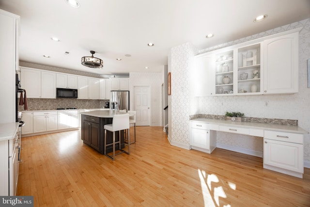 kitchen with white cabinetry, a kitchen breakfast bar, stainless steel fridge, a kitchen island, and light wood-type flooring