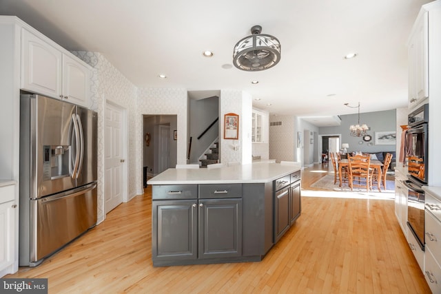 kitchen featuring a kitchen island, white cabinets, stainless steel fridge with ice dispenser, light hardwood / wood-style floors, and oven