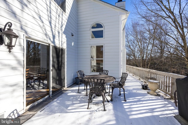 snow covered patio with a wooden deck