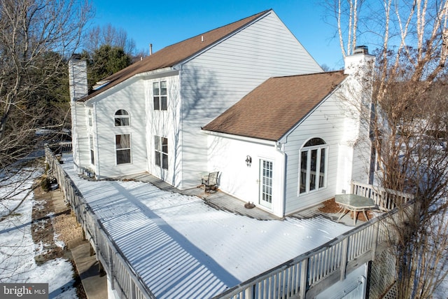 snow covered back of property with a wooden deck