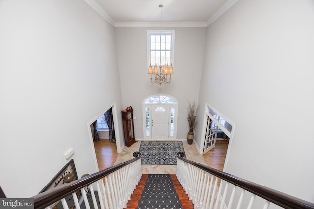 foyer with ornamental molding, a high ceiling, and an inviting chandelier