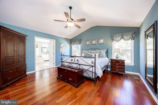 bedroom featuring hardwood / wood-style floors, connected bathroom, vaulted ceiling, and ceiling fan