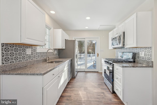 kitchen featuring sink, stainless steel appliances, dark hardwood / wood-style flooring, dark stone counters, and white cabinets