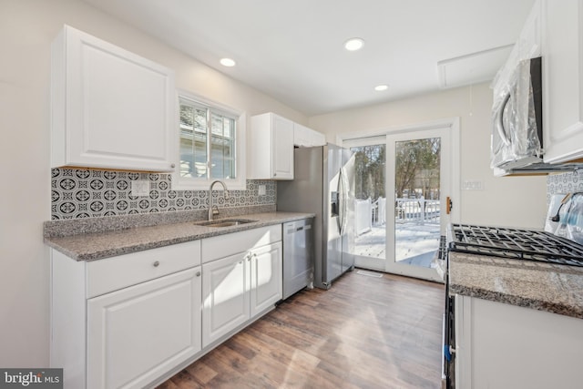 kitchen with dark stone counters, stainless steel appliances, dark wood-type flooring, sink, and white cabinetry