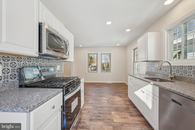 kitchen featuring appliances with stainless steel finishes, dark hardwood / wood-style flooring, light stone counters, sink, and white cabinets