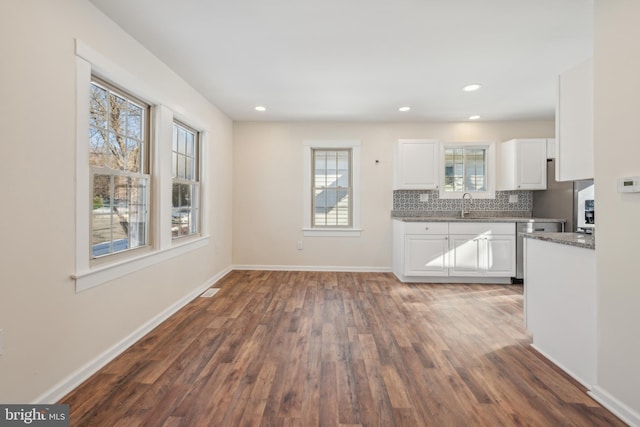 kitchen featuring white cabinets, sink, decorative backsplash, light stone countertops, and dark hardwood / wood-style flooring